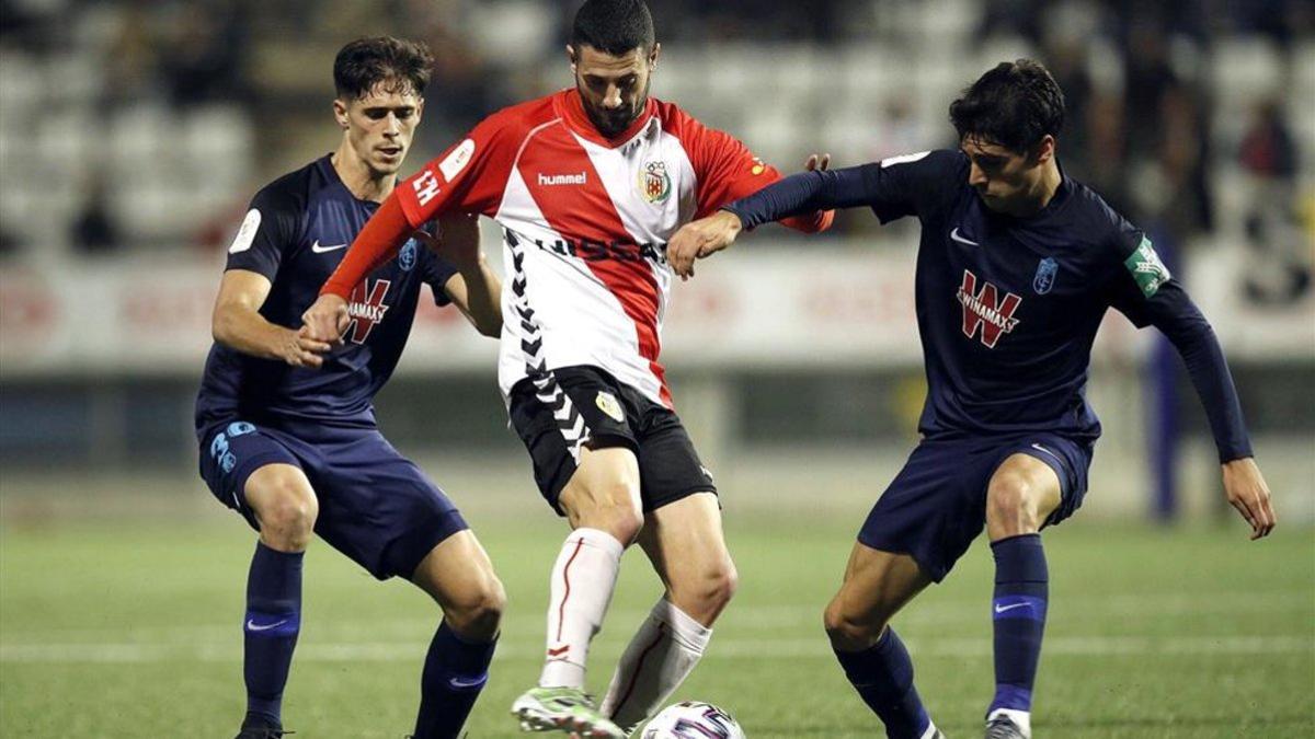 Salinas protege un balón antes dos jugadores del Granada