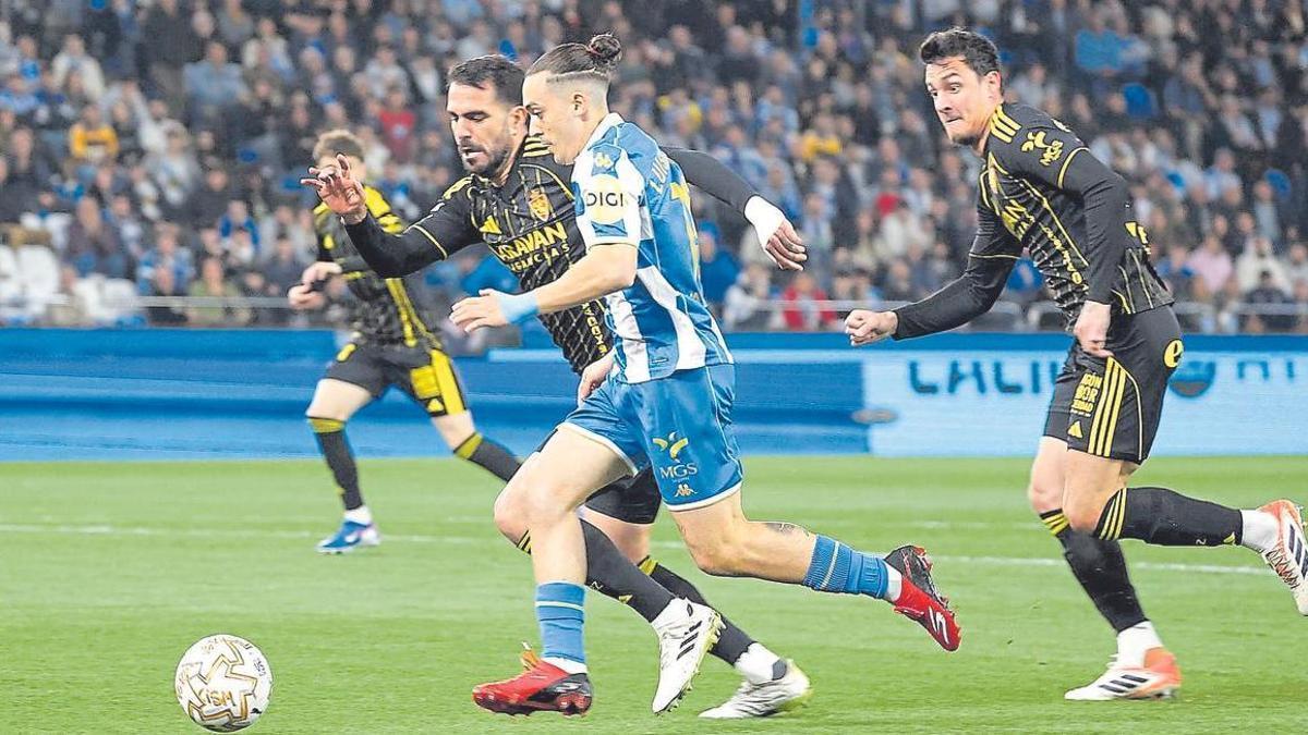 Insua y Radovanovic persiguen a Luismi Cruz en el partido ante el Deportivo.