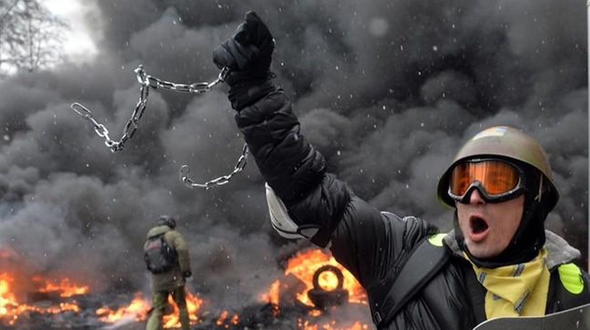 Un manifestant sosté una cadena i l’escut d’un antiavalots.