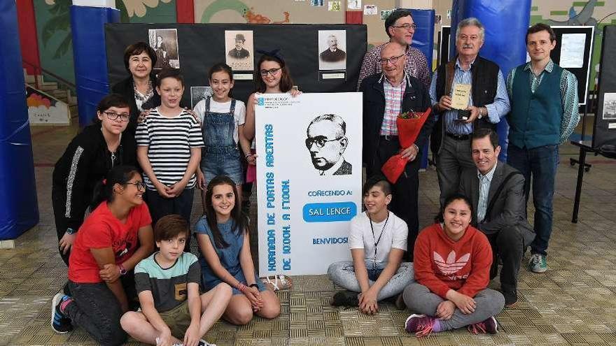 Estudiantes y docentes del centro posan junto a la exposición, con la directora a la izquierda.