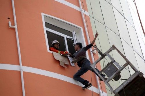 A firefighter tries to pull a worker into a window after he was trapped on a hanging platform in Liu'An, Anhui province