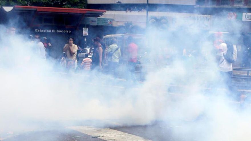 Manifestantes corren para huir de los gases lacrimógenos.