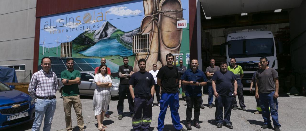 Trabajadores de Alusin Solar posan delante de la nave de la empresa en el PEPA, que luce sendos gratifis de inspiración asturiana (uno de ellos en la imagen) desde hace pocos días. | María Fuentes