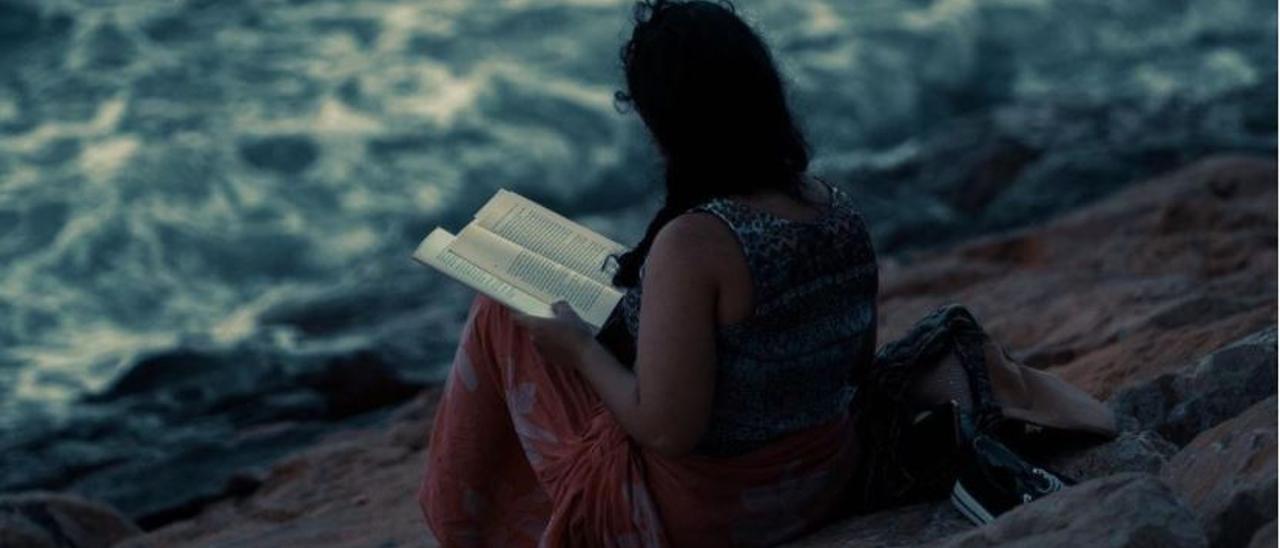 Una joven leyendo frente al mar retratada por David Olivas, fotógrafo y escritor