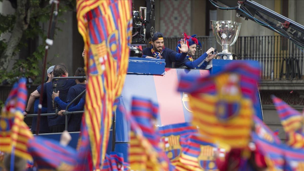 Suárez e Iniesta, junto a las copas, durante la rúa del Barça.