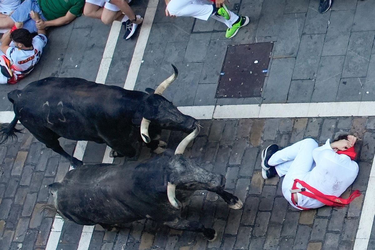 PAMPLONA, 08/07/2025.- Un corredor se protege al paso de varios toros de la ganadería Cebada Gago en el tramo de la Estafeta durante el segundo encierro de los Sanfermines este martes, en Pamplona. EFE/ Ainhoa Tejerina