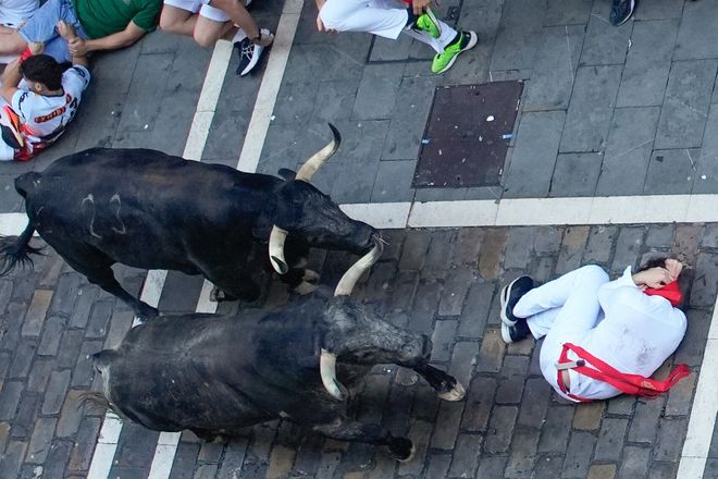 PAMPLONA, 08/07/2025.- Un corredor se protege al paso de varios toros de la ganadería Cebada Gago en el tramo de la Estafeta durante el segundo encierro de los Sanfermines este martes, en Pamplona. EFE/ Ainhoa Tejerina