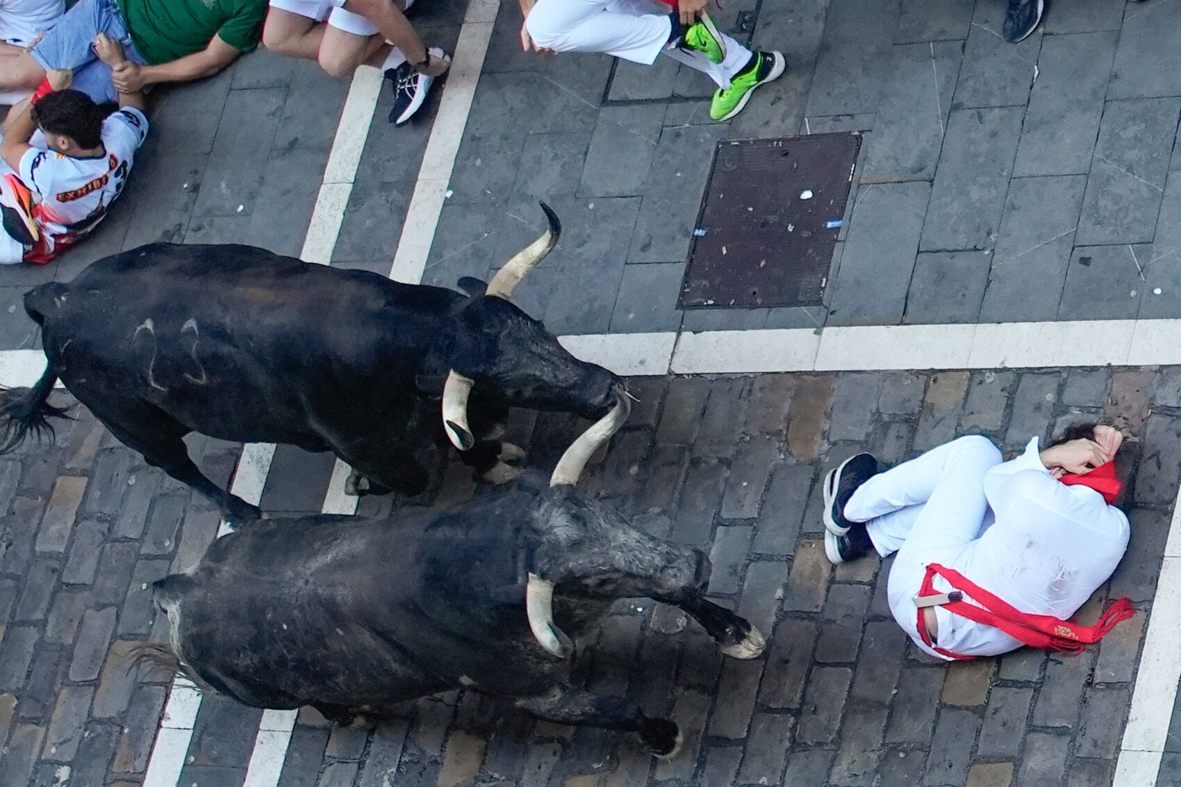 PAMPLONA, 08/07/2025.- Un corredor se protege al paso de varios toros de la ganadería Cebada Gago en el tramo de la Estafeta durante el segundo encierro de los Sanfermines este martes, en Pamplona. EFE/ Ainhoa Tejerina