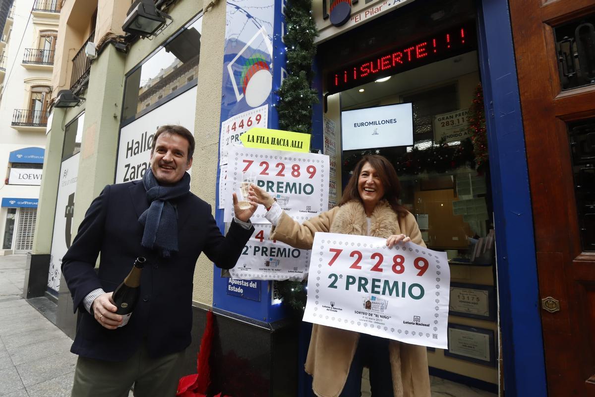 La responsable de la administración número 2 de Zaragoza brinda con champán mientras muestra el cartel con el número agraciado con el segundo premio, el 72289.