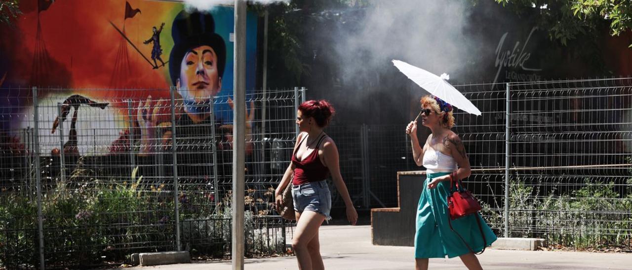 Unos turistas intentan refrescarse en unos vaporizadores de agua fresca en Barcelona.