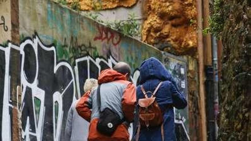 Peatones pasando junto a un grafiti