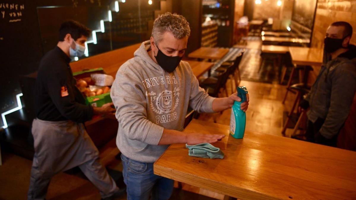 Un hostelero desinfecta una mesa de un local en la calle de la Barrera, en A Coruña. |   // CARLOS PARDELLAS