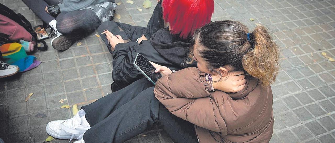Una adolescente consultando su móvil.