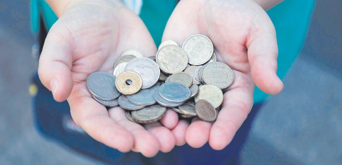Una persona enseña un puñado de monedas antiguas.