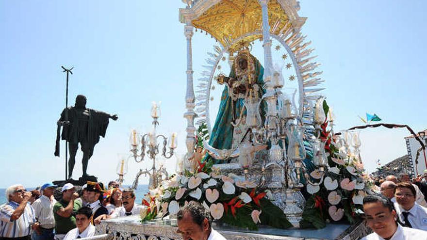 El investigador Enrique Vivancos. A la derecha, la actual imagen de la Virgen de Candelaria en procesión, a su paso por la escultura de uno de los históricos guanches en el municipio tinferfeño.