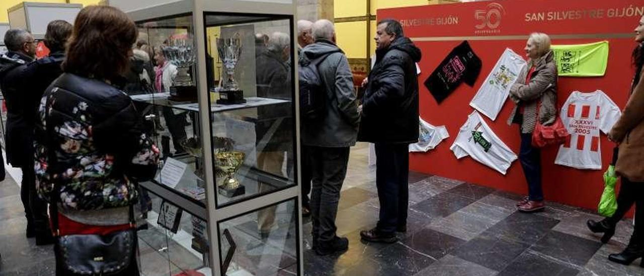 Asistentes a la inauguración ante la vitrina de trofeos y el panel de camisetas.