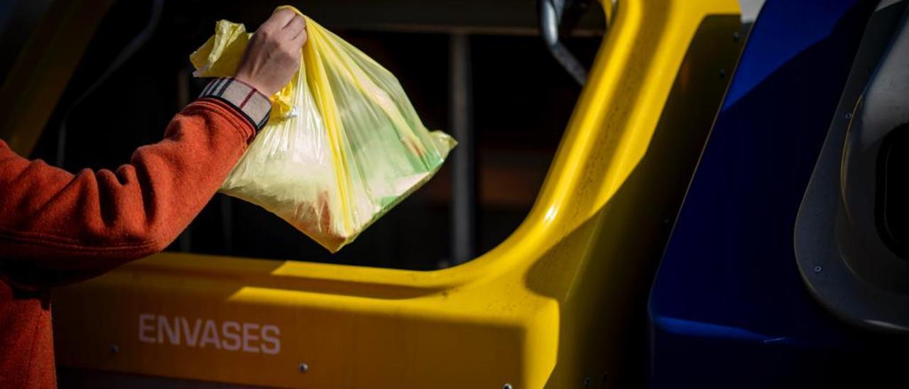 Una persona deposita una bolsa con plásticos en el contenedor amarillo destinado al reciclaje de envases.