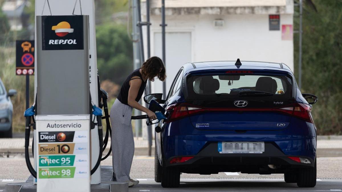 Una mujer reposta combustible en una gasolinera en una foto de archivo