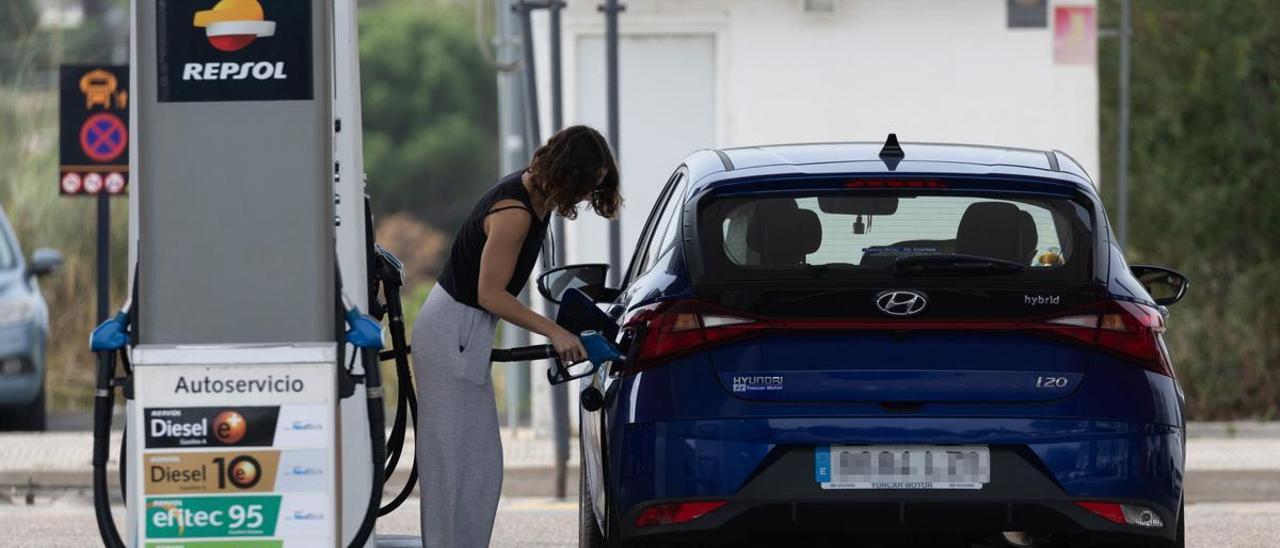 Una mujer reposta combustible en una gasolinera.