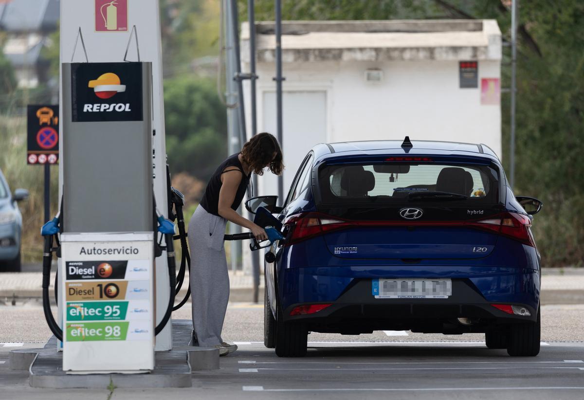 Una mujer reposta combustible en una gasolinera.