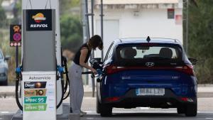 Una mujer reposta combustible en una gasolinera.