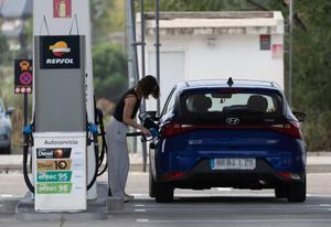 Una mujer reposta combustible en una gasolinera.