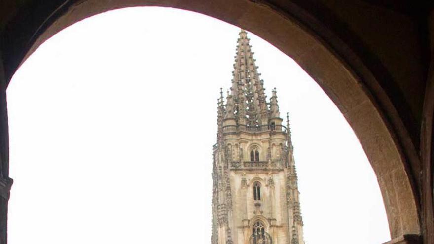 Un grupo de turistas pasea ante la Catedral en un día de lluvia.