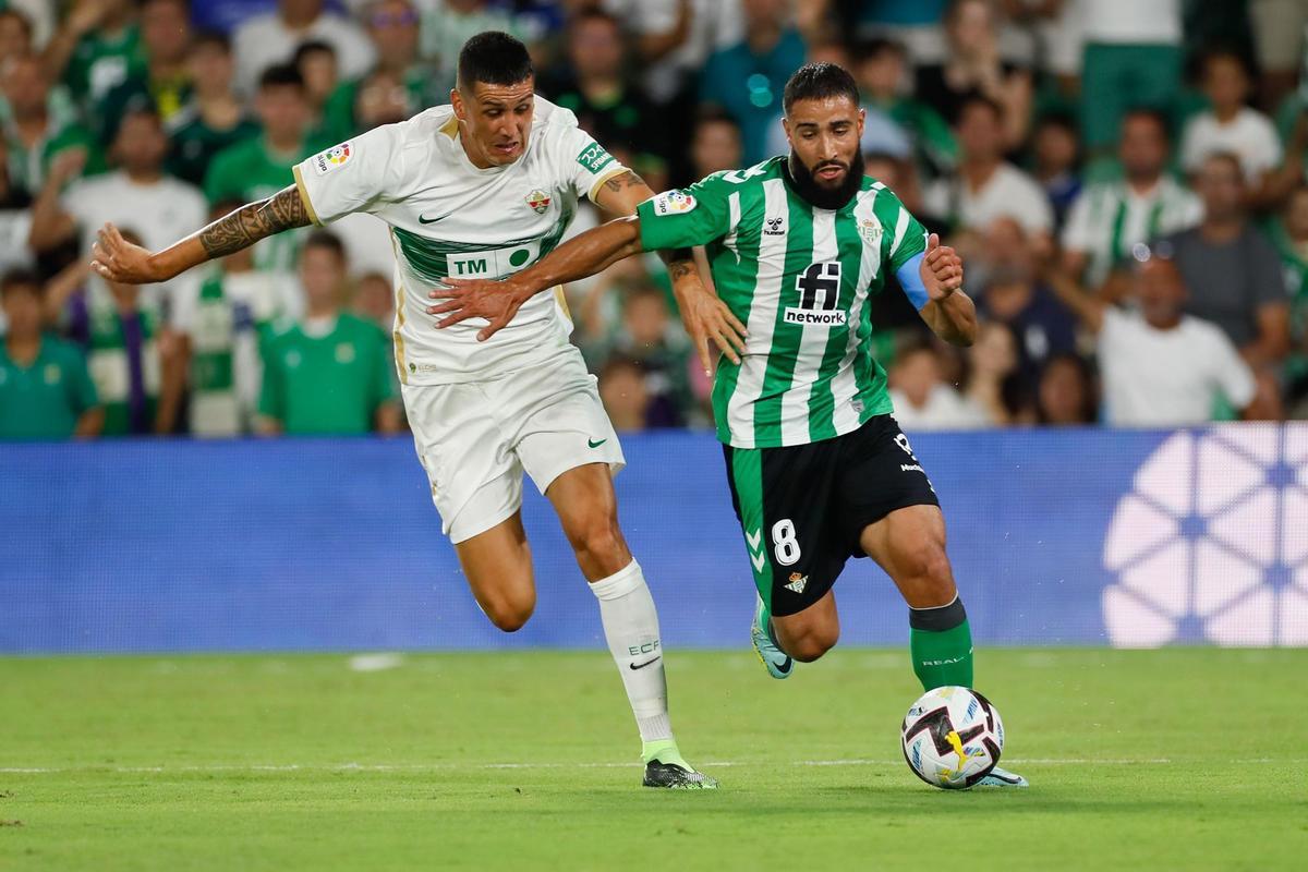 SEVILLA, 15/08/2022.- El centrocampista francés del Real Betis Nabil Fekir (d) se escapa del chileno Enzo Roco, del Elche CF, durante el partido de la primera jornada de Liga en Primera División que Real Betis y Elche CF disputan hoy lunes en el estadio Benito Villamarín, en Sevilla. EFE/José Manuel Vidal