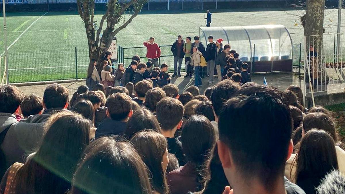 Luis López, al fondo, con todas las cabezas de los alumnos mirando hacia él en su último día en el colegio.