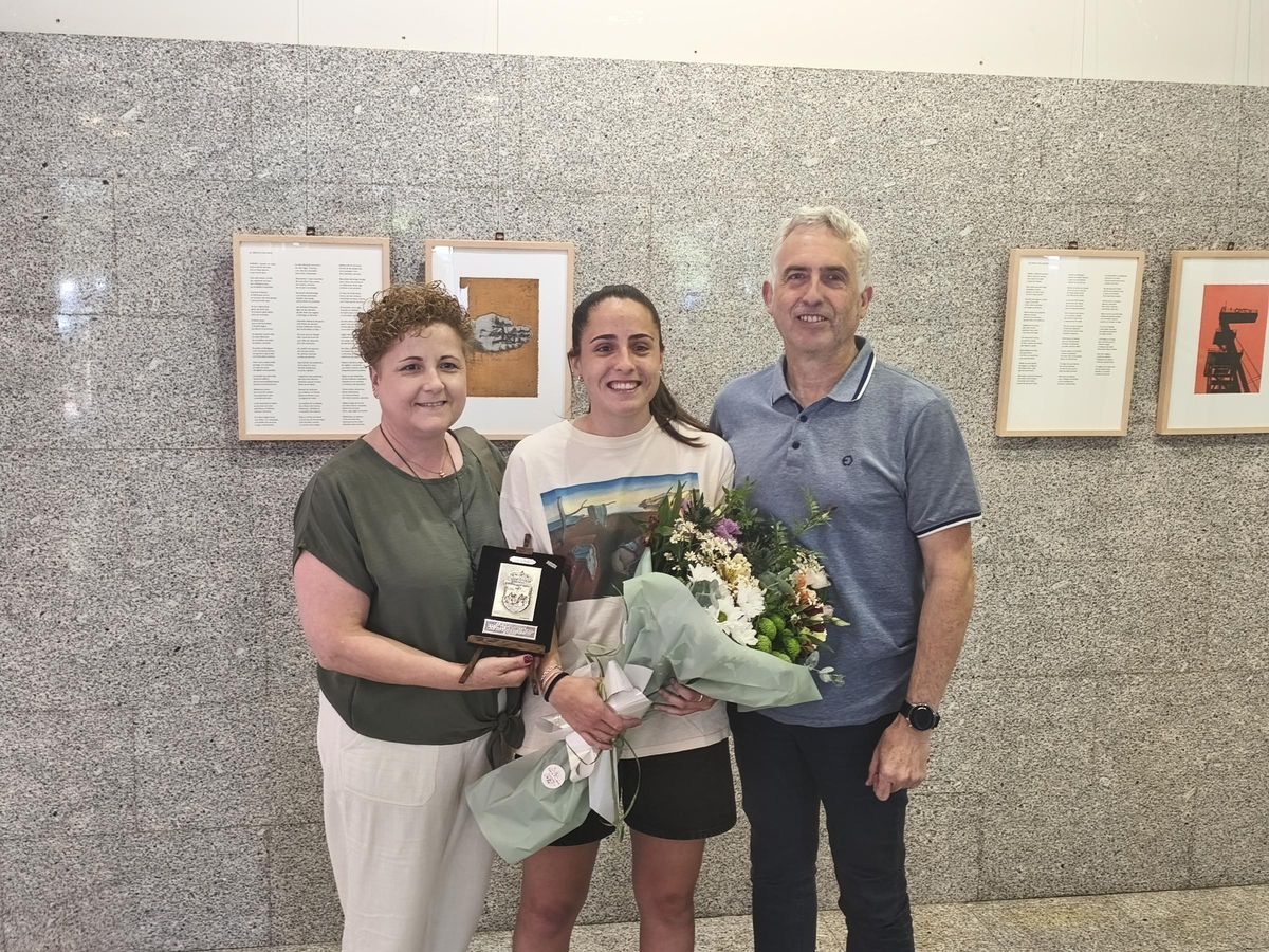 La futbolista y su familia, posando con el ramo de flores y la placa.
