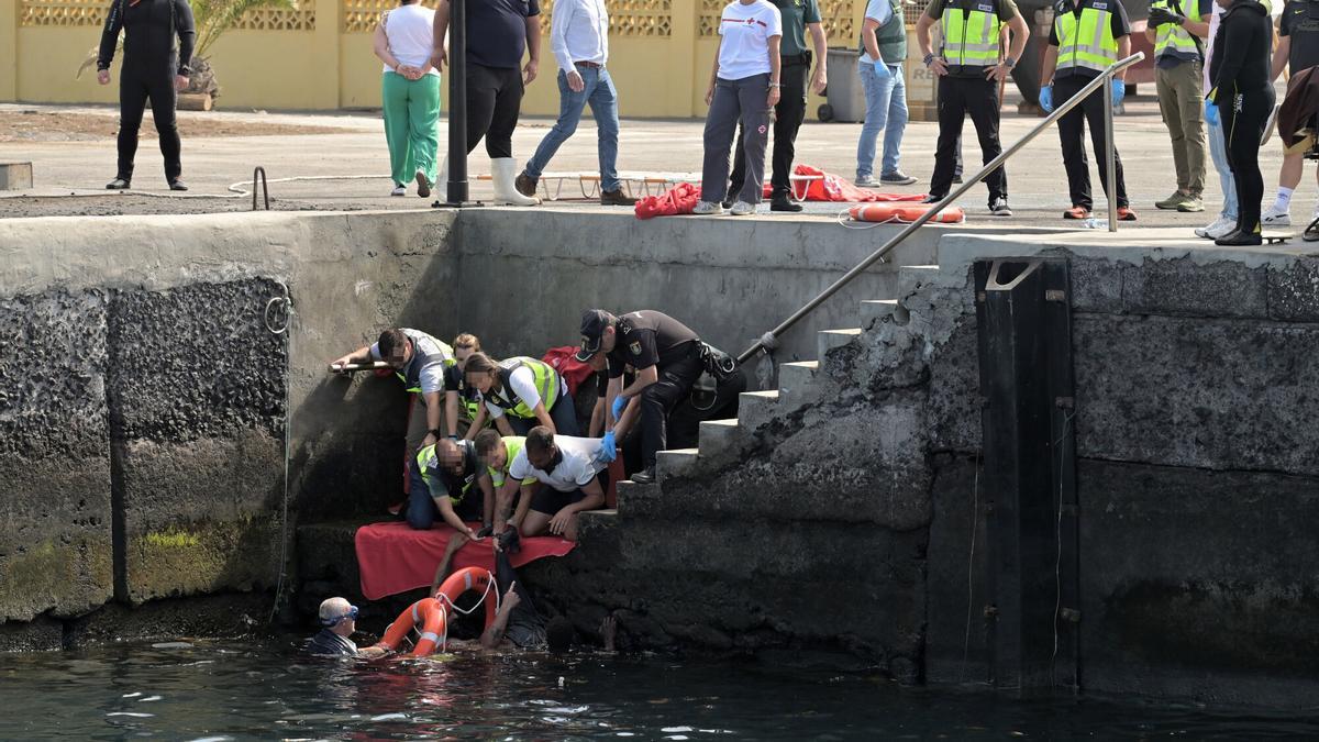 Agentes de Policía Nacional rescatan a uno de los migrantes que viajaba en el cayuco que ha volcado a su llegada al puerto de La Restinga, en El Hierro, Canarias