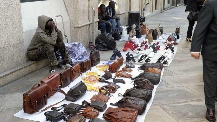 &#039;Manteros&#039; venden bolsos y calzado en una calle céntrica de A Coruña.