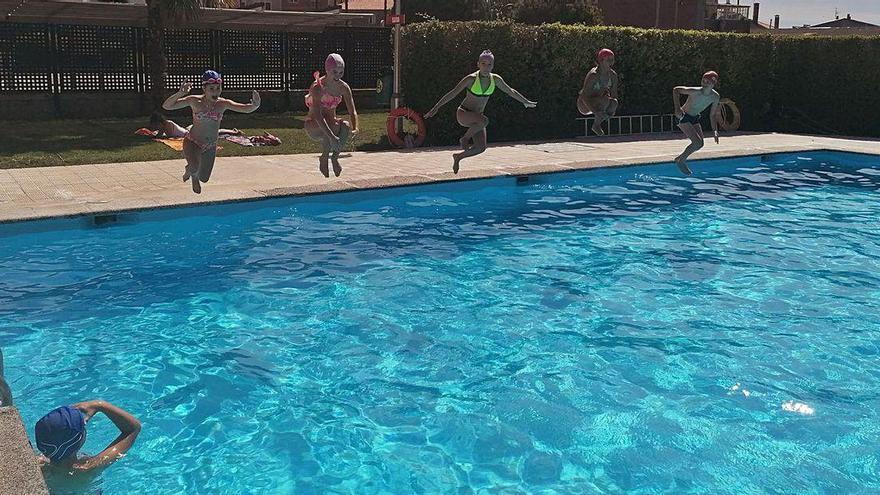 Un grupo de jóvenes se zambullen en la piscina en la primera jornada de apertura al público.