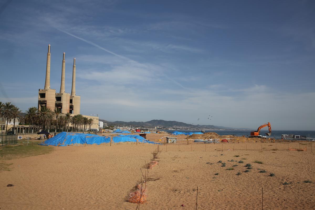 Obras para extender un cable de fibra óptica en la playa contaminada de Sant Adrià, con las Tres Xemeneies al fondo.