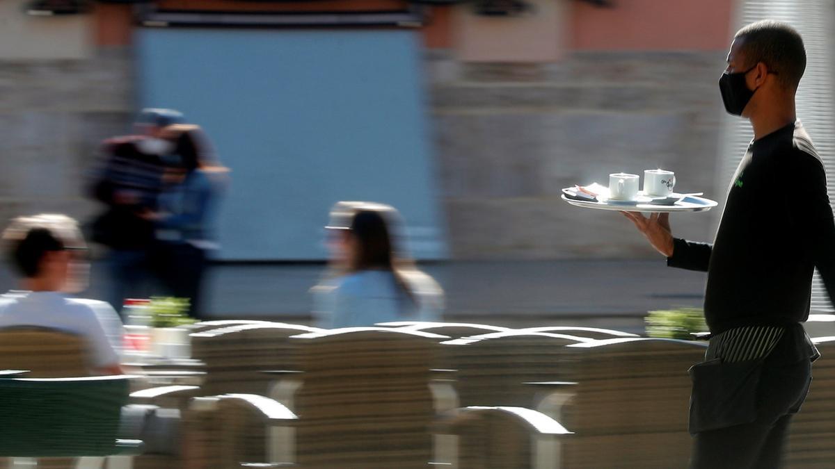 Un camarero lleva unos cafés en una bandeja.