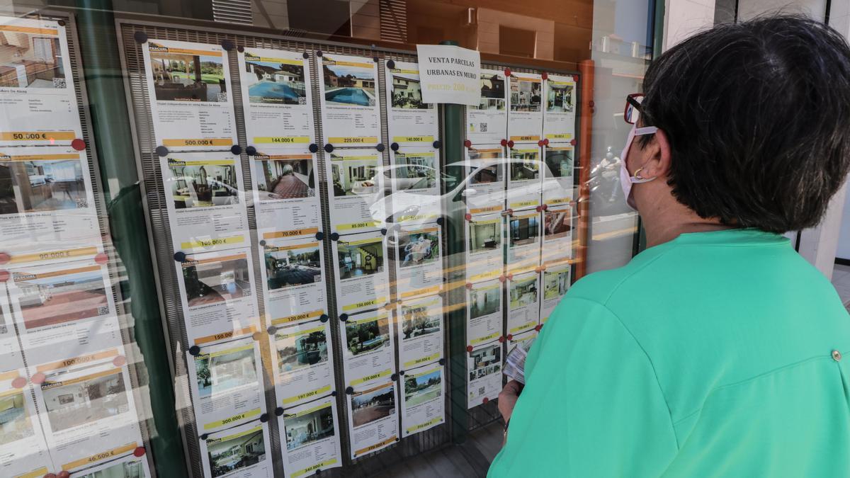 A woman looks at the window of a real estate agency. A woman looks at the window of a real estate agency.