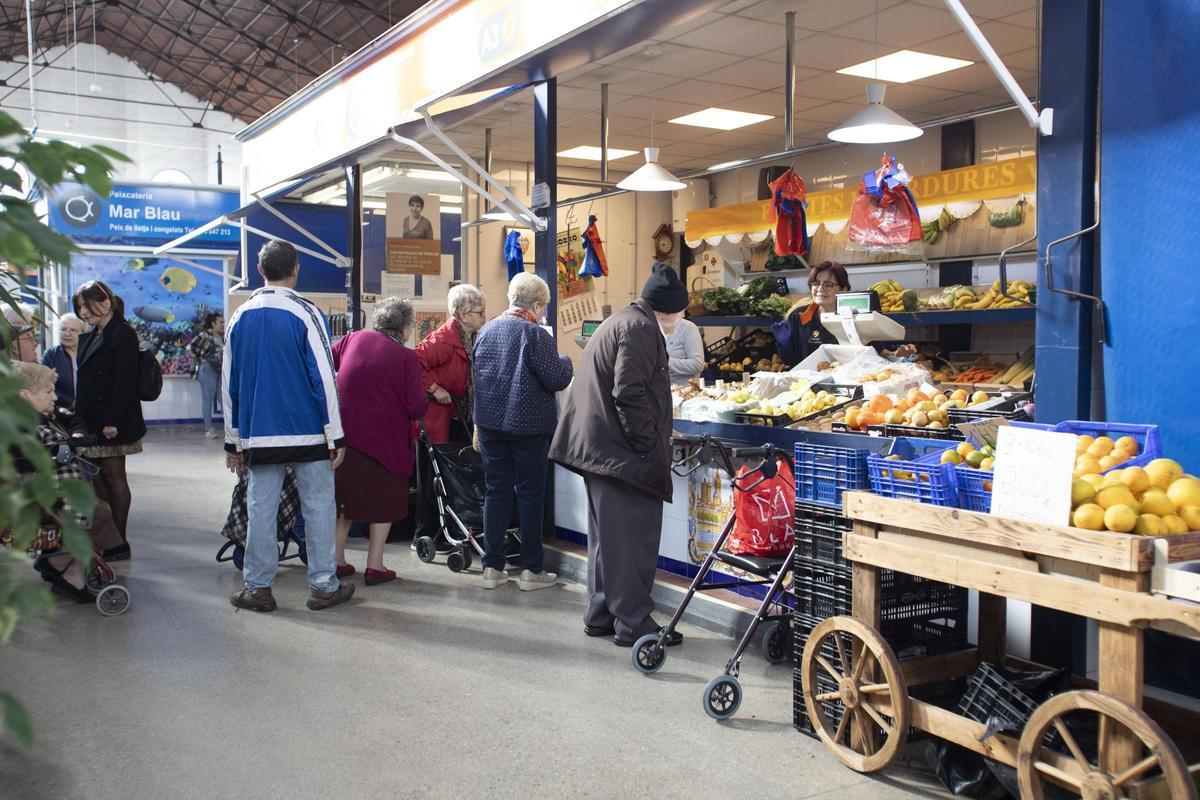 Un grupo de persona compra frutas y verduras en el mercado.