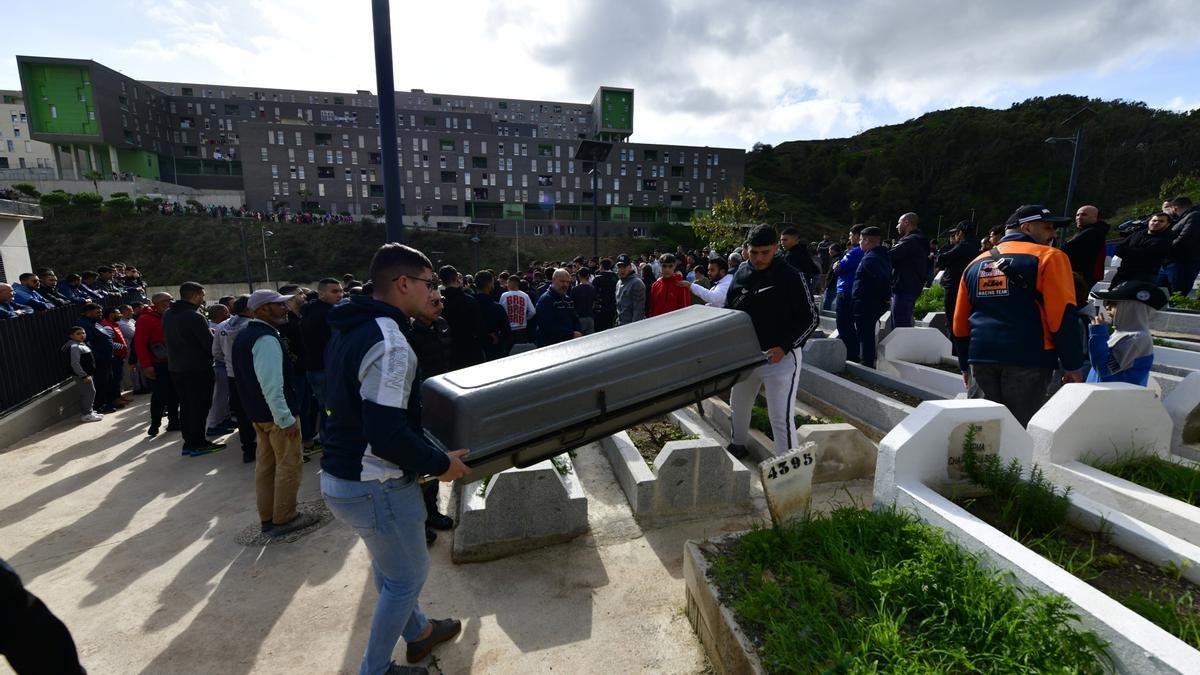 Dos personas transportan el féretro con los restos del niño de ocho años para su entierro en el cementerio musulmán Sidi Embarek, en Ceuta.