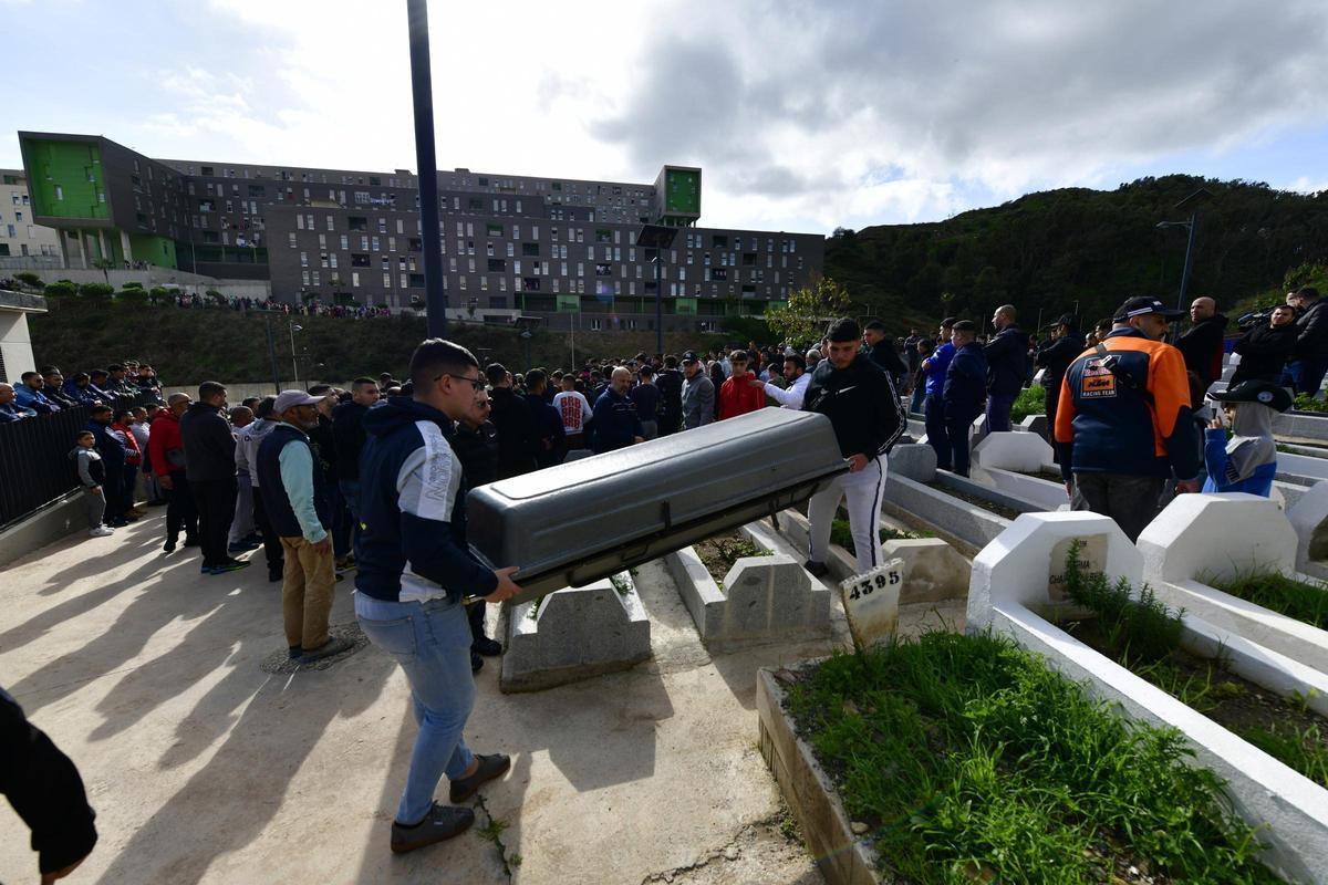 Dos personas transportan el féretro con los restos del niño de ocho años para su entierro en el cementerio musulmán Sidi Embarek, en Ceuta.