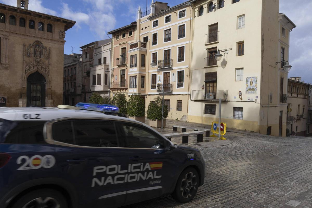Un coche de la Policía Nacional pasa por la Plaza de la Seu de Xàtiva, donde está la casa natalicia de Vicente Boix ocupada.