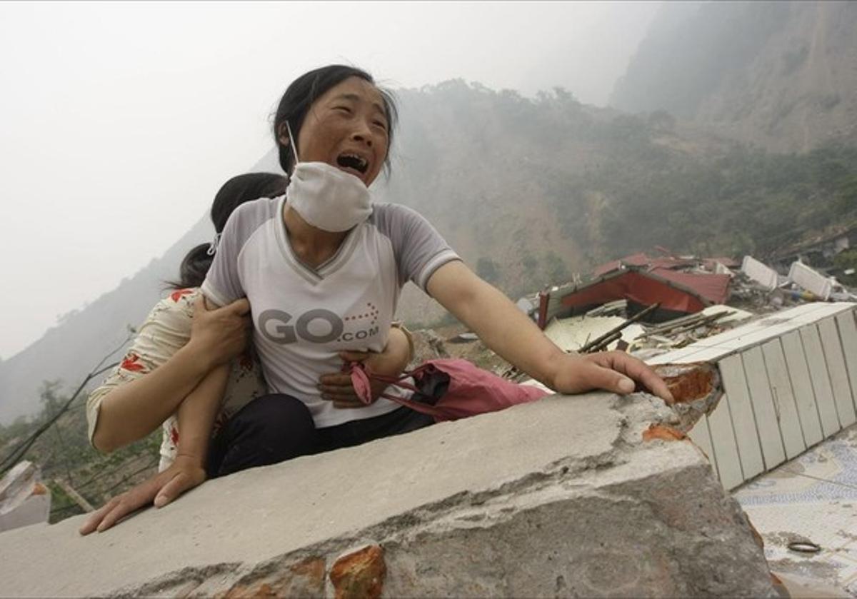 A woman cries as she cannot find her 4-year-old daughter and husband on the top of the ruins of a destroyed school in earthquake-hit Beichuan county, Sichuan province in this May 17, 2008 file photo.