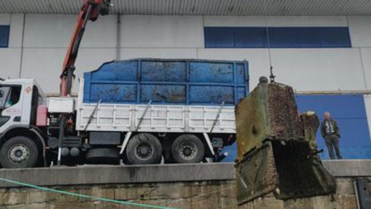 Una grúa iza un contenedor del fondo marino en O Berbés.