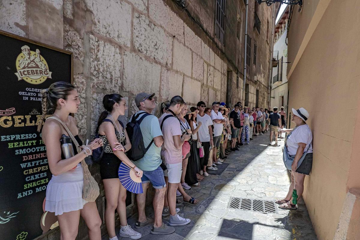 Un grupo de turistas sigue las explicaciones de una guía turística en el casco antiguo de Palma.