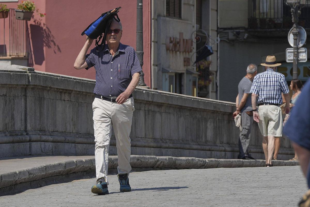 Un vianant es protegeix del sol en plena onada calor a Girona