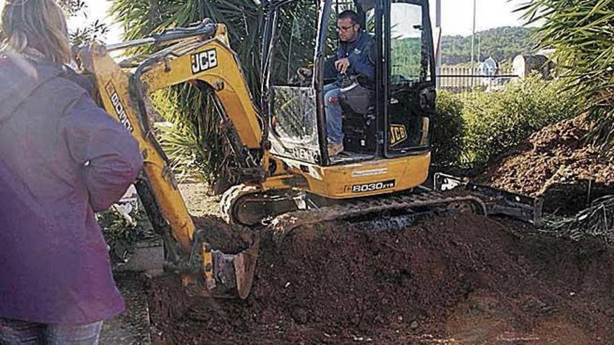 Una excavadora de pequeñas dimensiones retirando tierra de la fosa común ayer por la mañana.