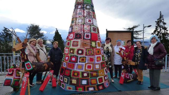 Por la izquierda, Otilia Feito, Olvido Fernández, Aurelia Peláez, Beatriz Suárez, Trinidad Lobato, América Llano, la edil Mayte Ruiz y Toña Cancio, ante el árbol que tejieron junto a otras asociaciones del concejo. | D. Á.