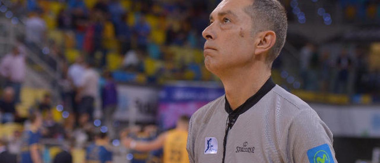 El árbitro Juan Carlos Arteaga con un balón en una cancha de baloncesto.