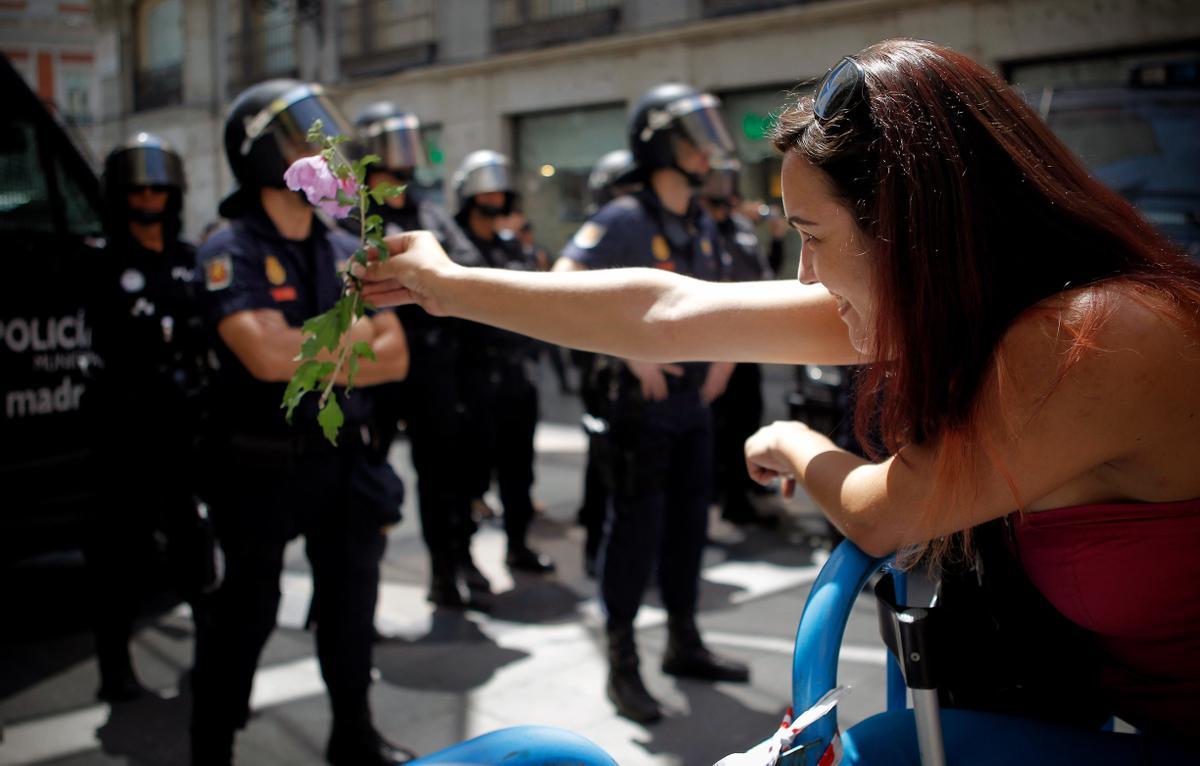 Una mujer ofrece una flor a un agente de la policia durante una de las protestas del 15-M.