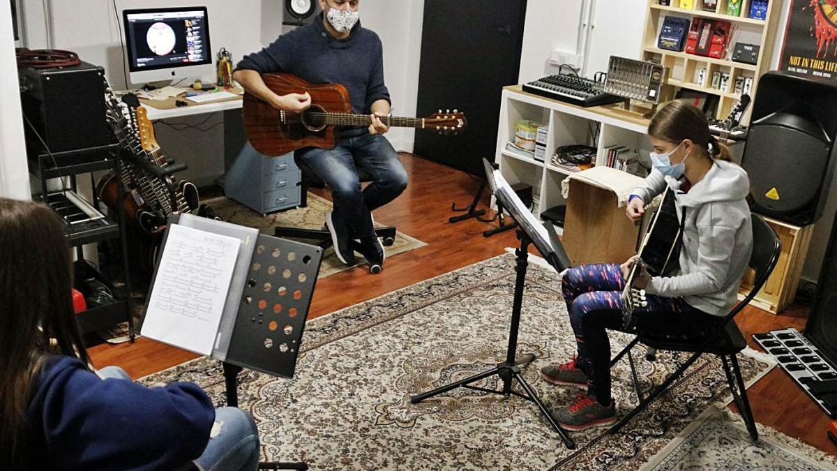 Un professor de música fent una classe amb dues alumnes.