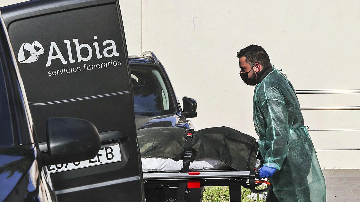 Un operario traslada a una persona fallecida por covid-19 en un hospital de València. | F.CALABUIG